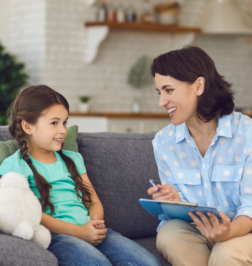 Smiling Little Girl Talks to a Cheerful Child Psychotherapist during a Therapy Session in the Office.